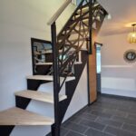 Escalier quart tournant en métal noir avec marches en bois et garde-corps sur mesure dans un intérieur contemporain.